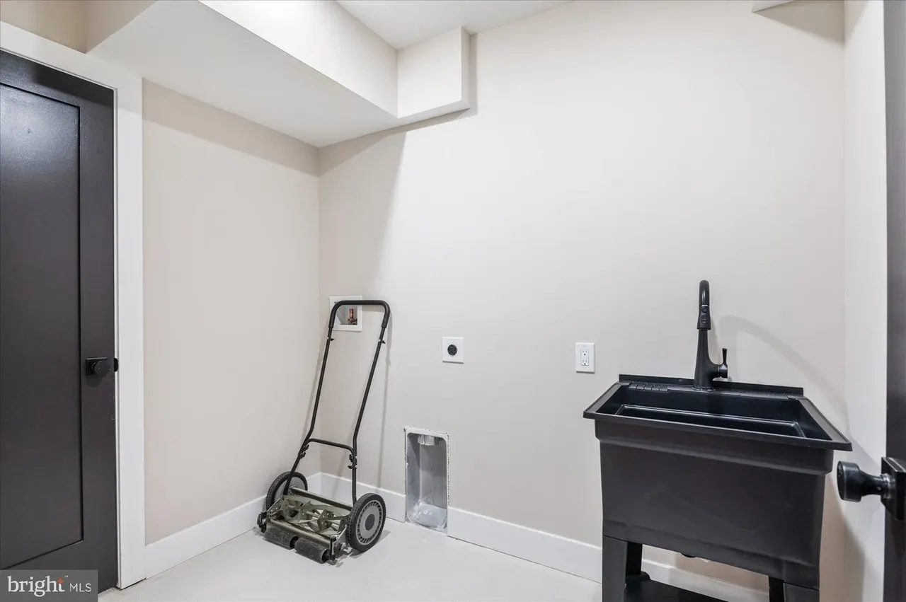 Utility room with lawn mower, sink, and black door