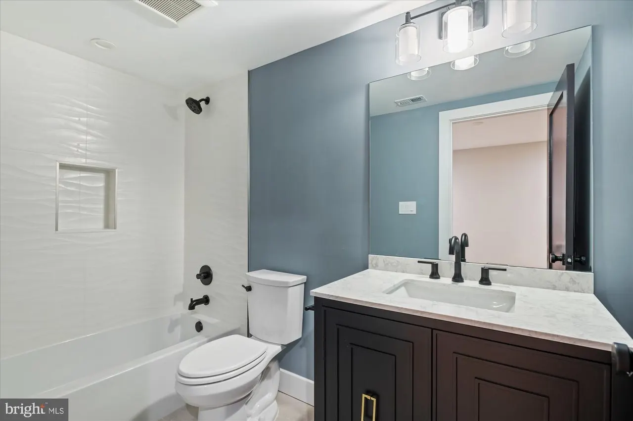 Bathroom with teal accent wall, dark vanity, and white subway tile