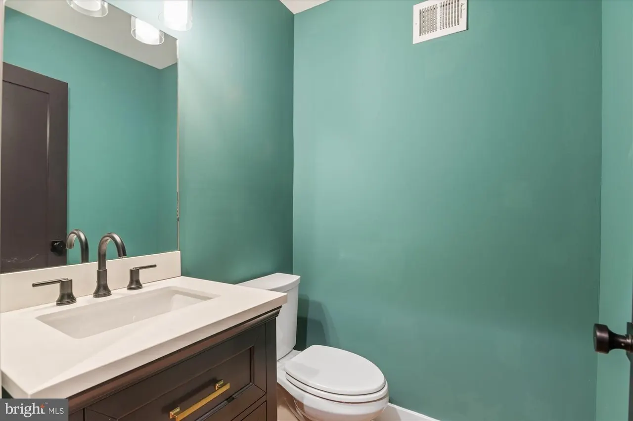 Bathroom with turquoise walls, dark vanity, and white countertop