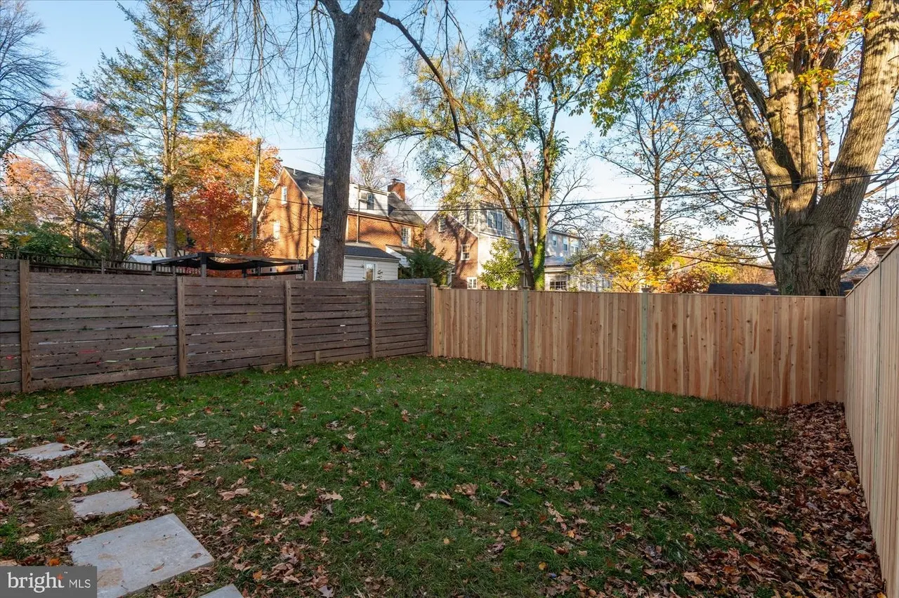 Fenced backyard with green lawn and stepping stone pathway