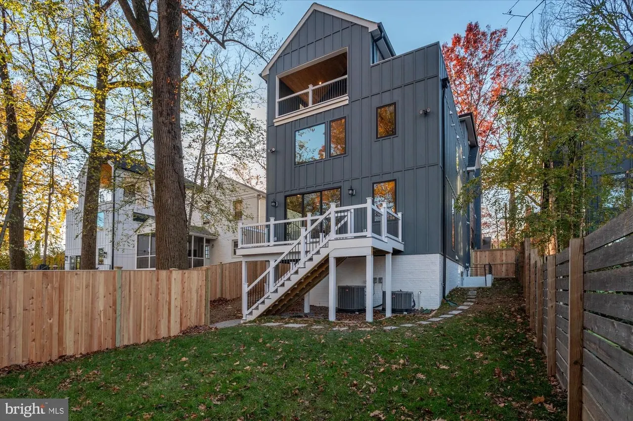 Modern black and white exterior with deck stairs and fenced yard