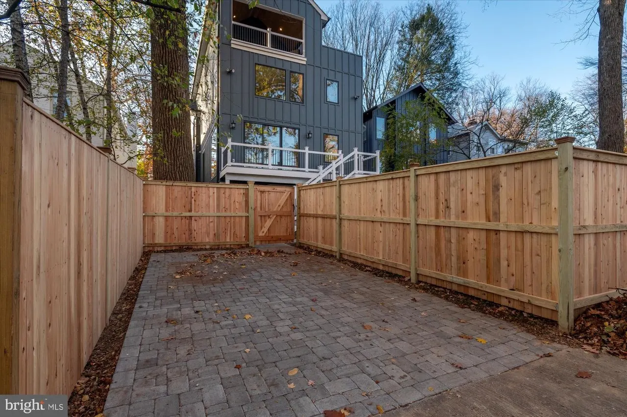 Paver patio area surrounded by wood fence with house backdrop