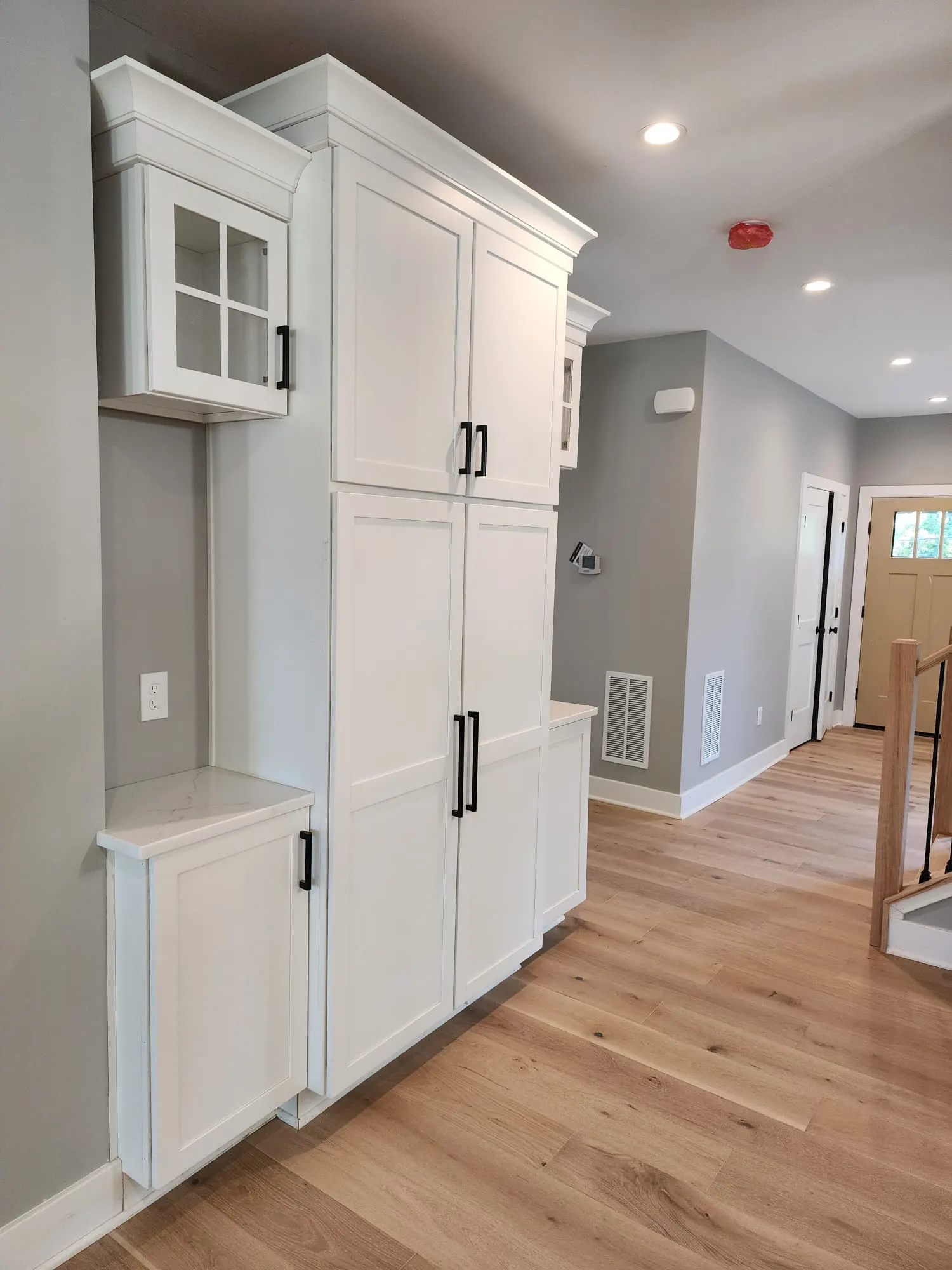 White pantry cabinets with black hardware along entry hallway