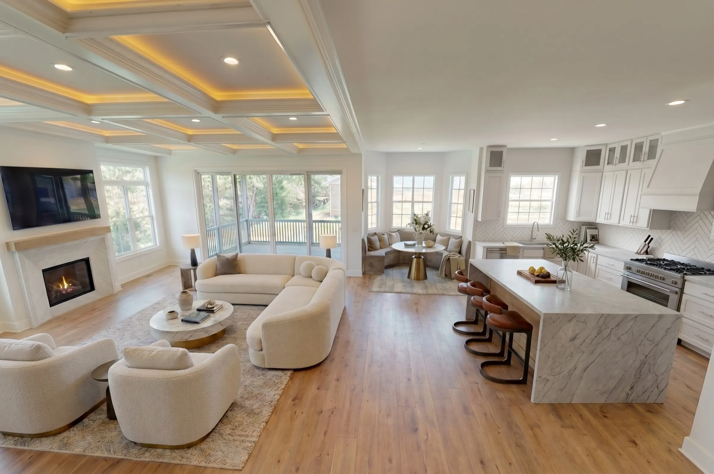 Open-plan great room with coffered cove ceiling, gas fireplace, marble waterfall island, and circular breakfast banquette