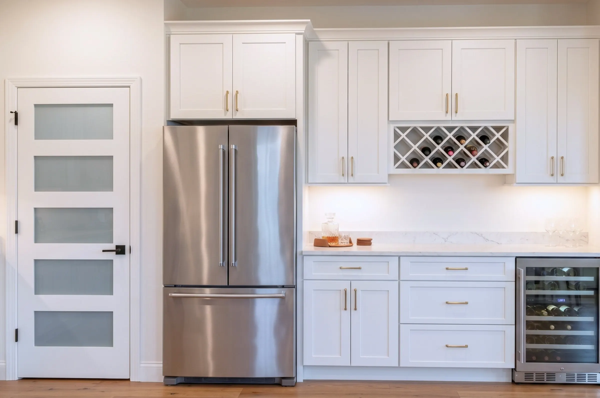 Beverage bar with French-door refrigerator, built-in wine rack, under-counter wine cooler, and brass pulls