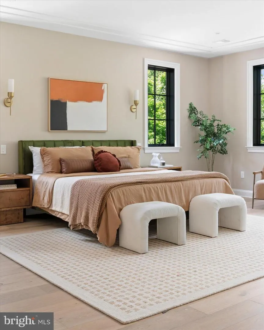 Primary bedroom with green upholstered bed and black windows