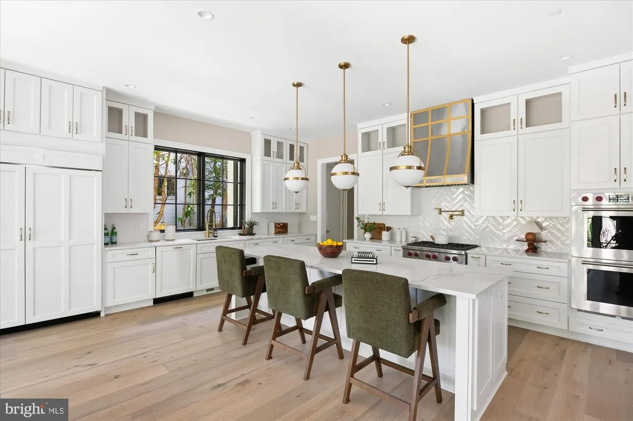 Modern kitchen with white cabinets, island, and brass pendant lights