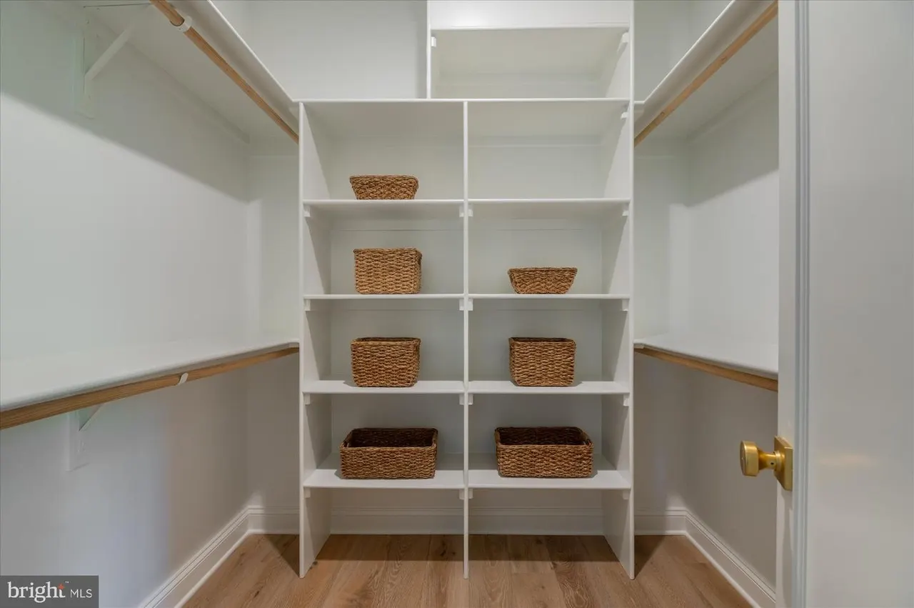 Walk-in closet with white shelving and woven storage baskets