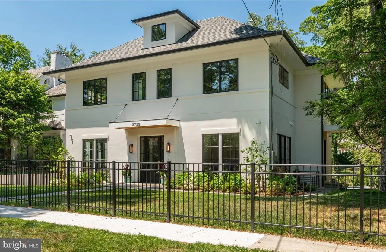 Modern white house exterior with black-trimmed windows and iron fence