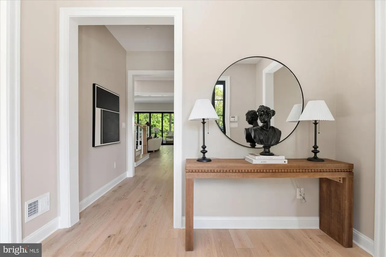 Foyer with console table, round mirror, and hardwood flooring