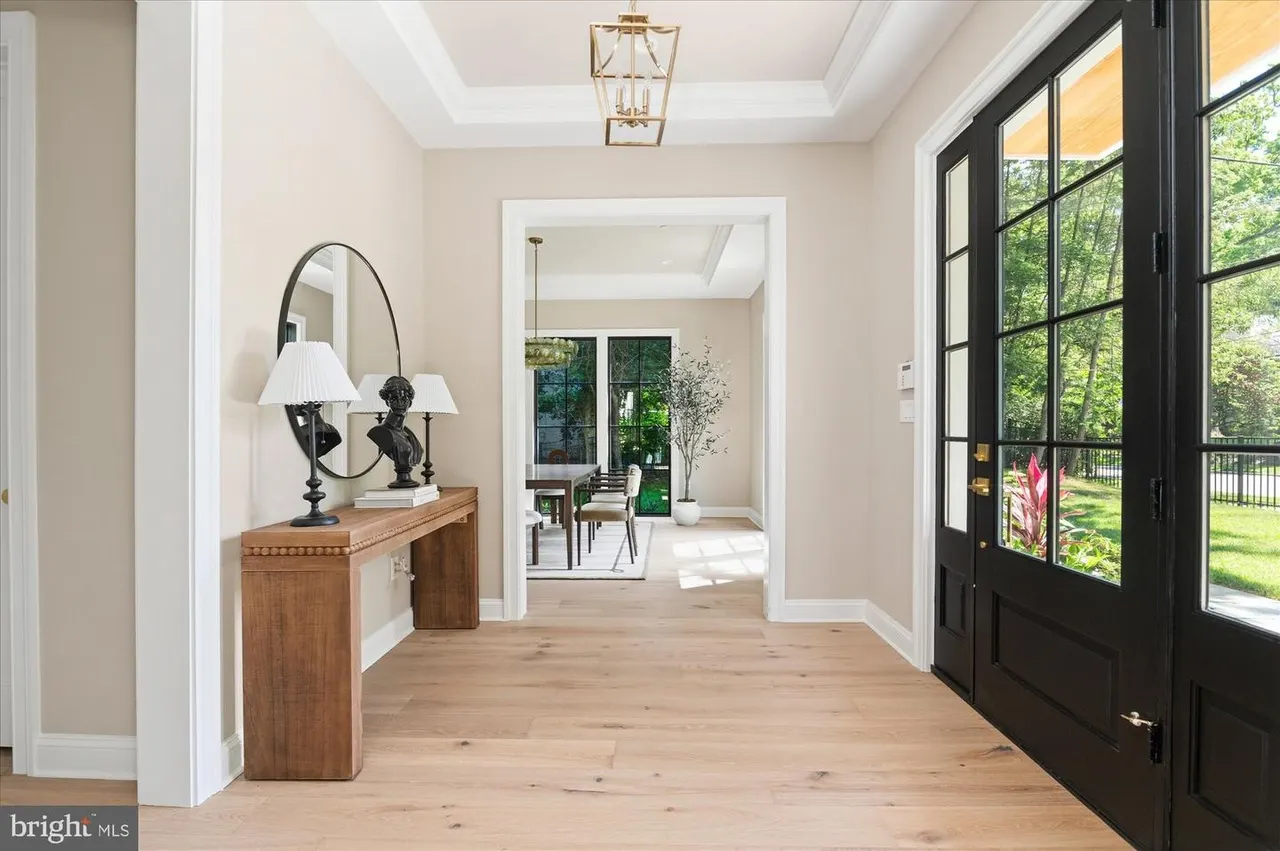 Entry hall with wooden console, black glass doors, and pendant light
