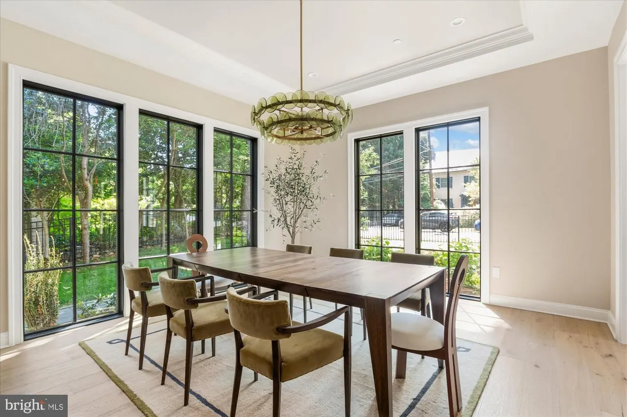 Dining room with wood table, upholstered chairs, and large windows