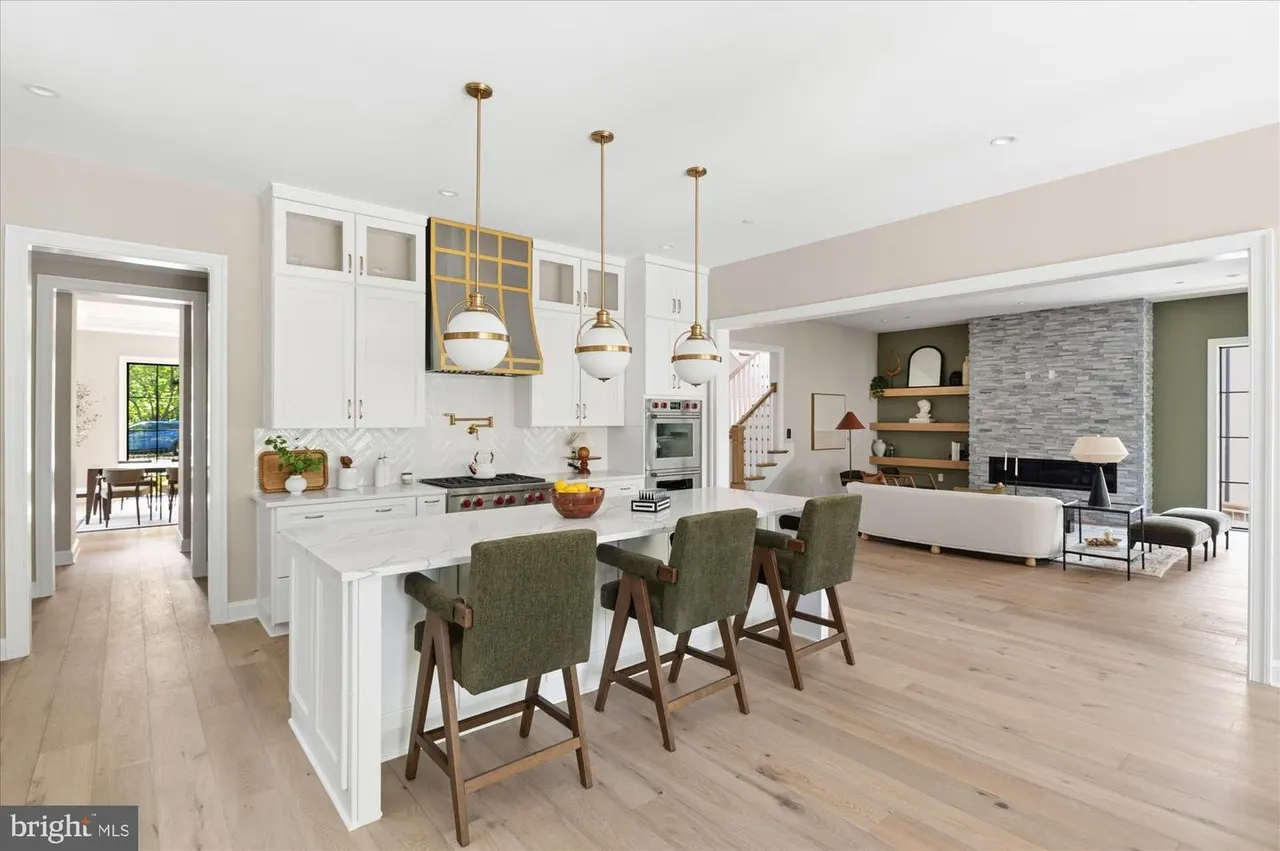 Open kitchen with white cabinetry, island seating, and brass lighting