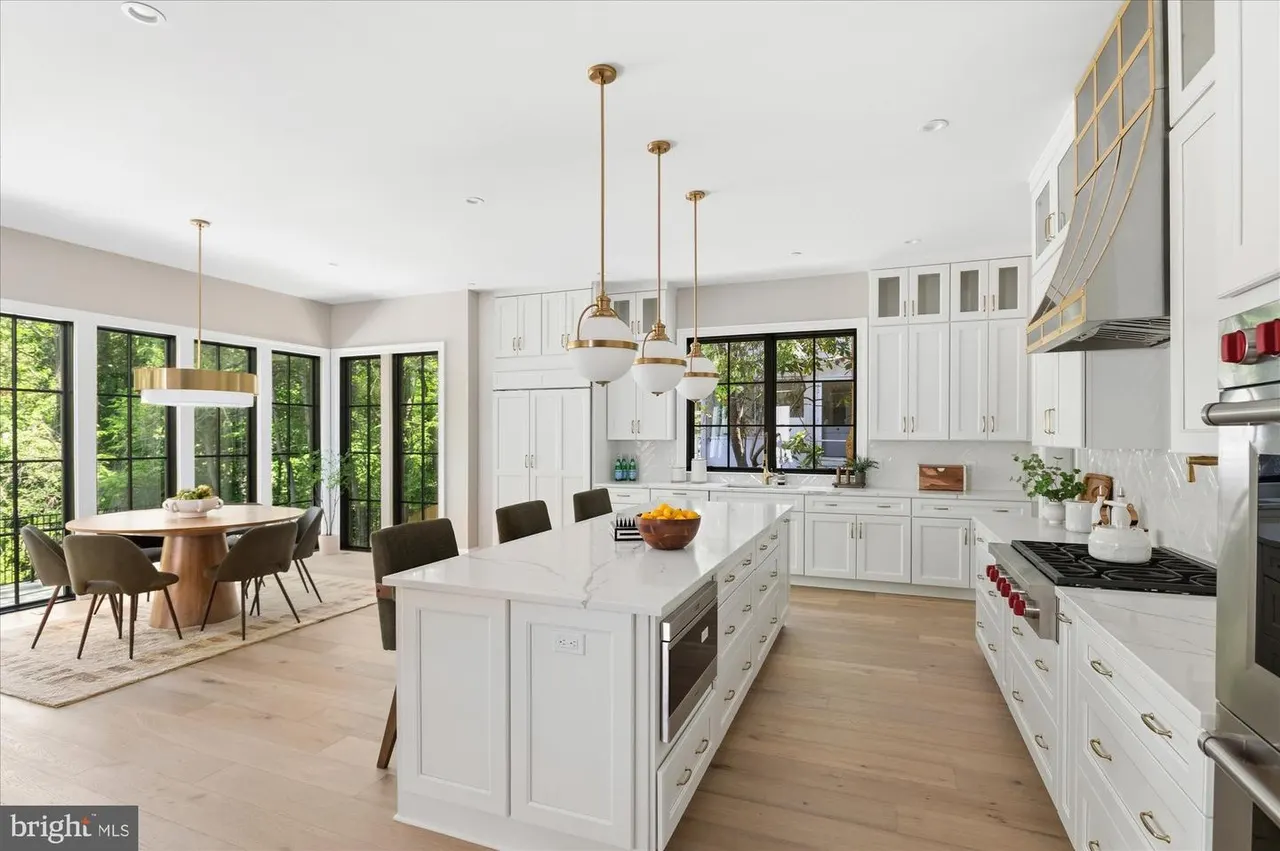 Large kitchen with white cabinetry, marble island, and multiple windows