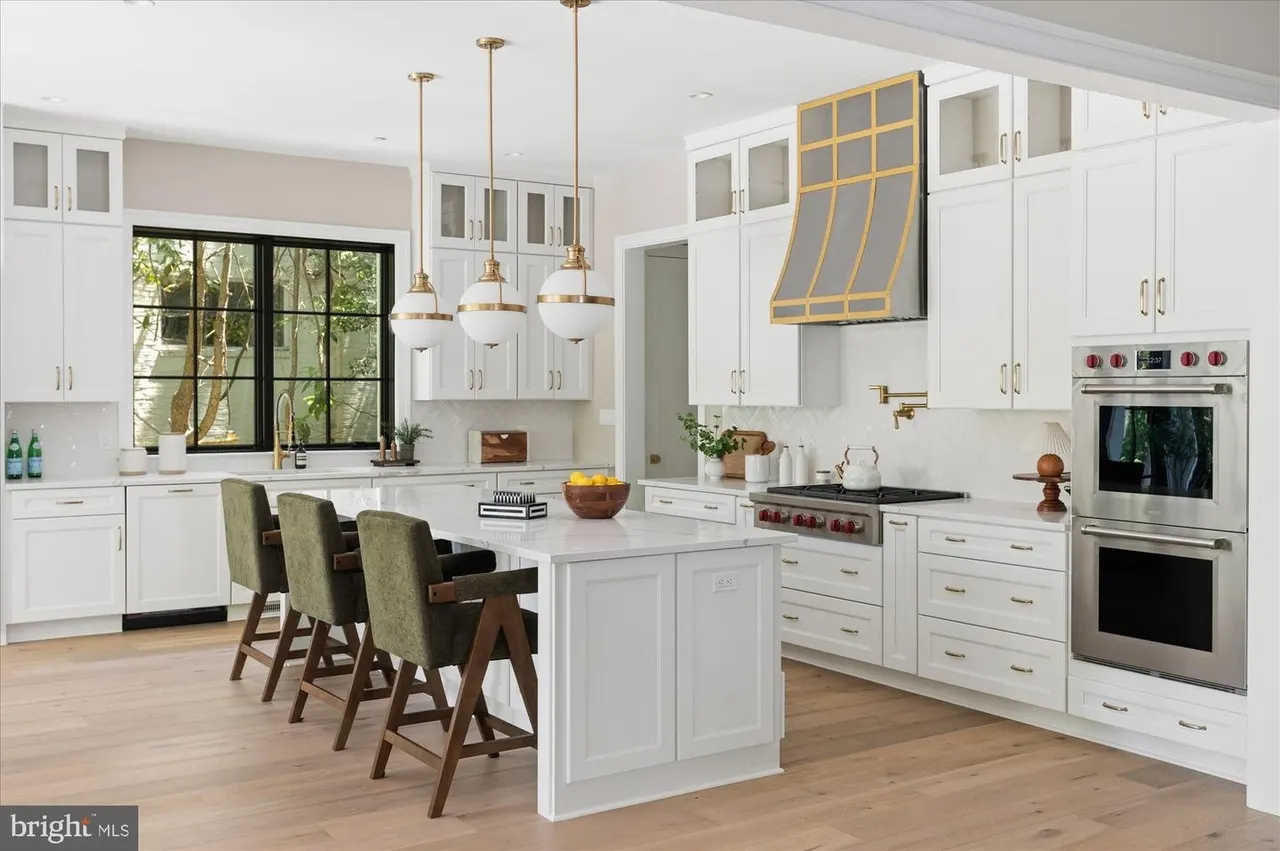 Kitchen with white cabinetry, dual ovens, and island seating