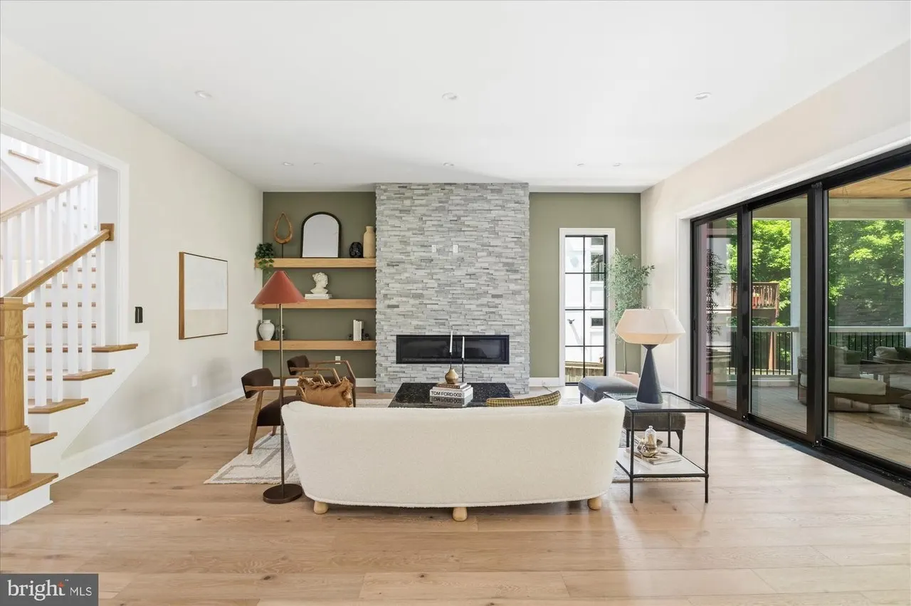 Open living room with stone fireplace, cream sofa, and glass doors