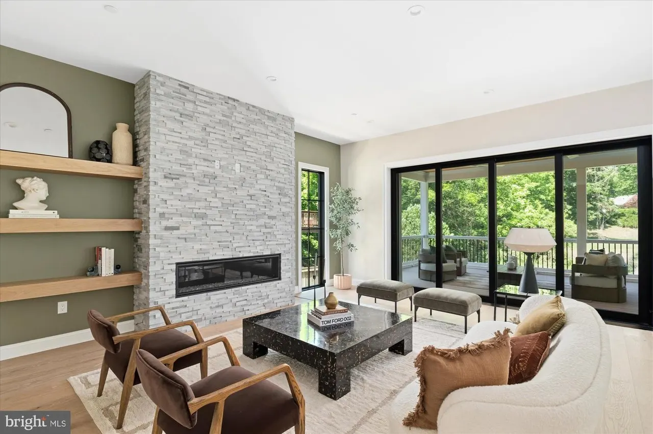 Living room with stone fireplace, wood shelving, and terrace access