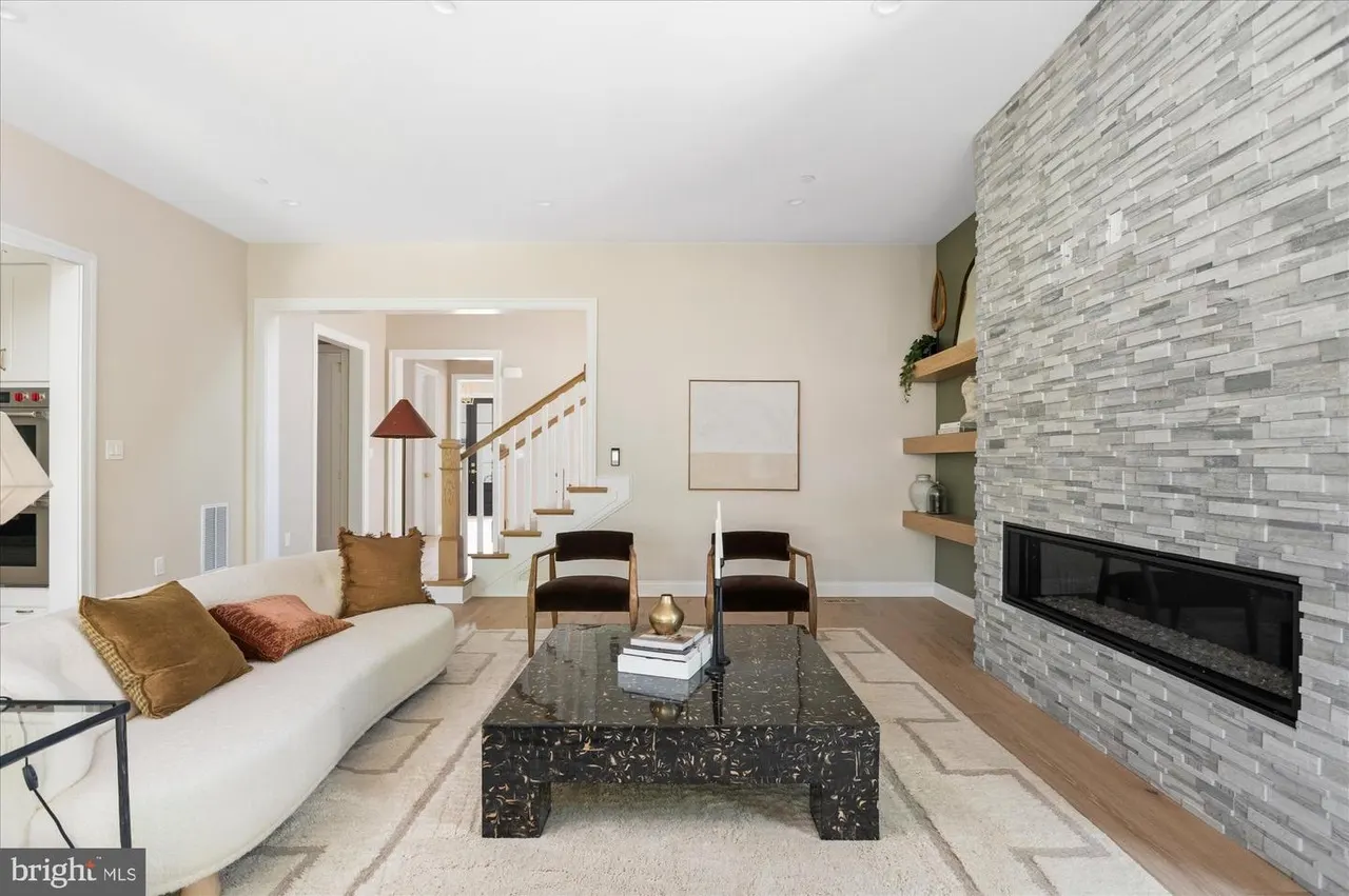 Living room with cream sofa, stone fireplace, and staircase
