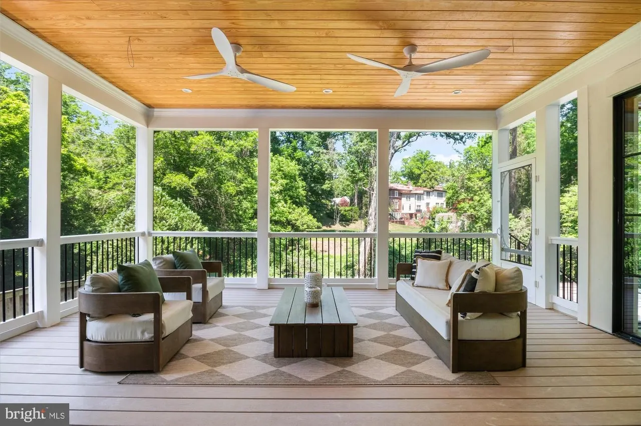 Screened porch with wood ceiling, furniture, and wooded views