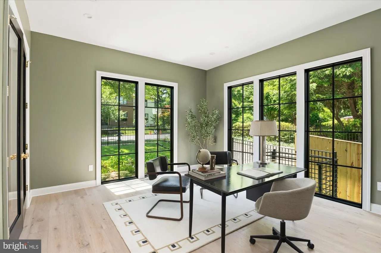 Office with sage walls, multiple windows, black desk and chairs