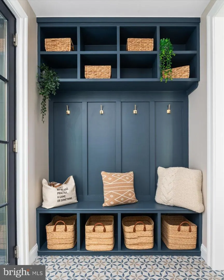 Mudroom with navy built-in shelving and woven basket storage