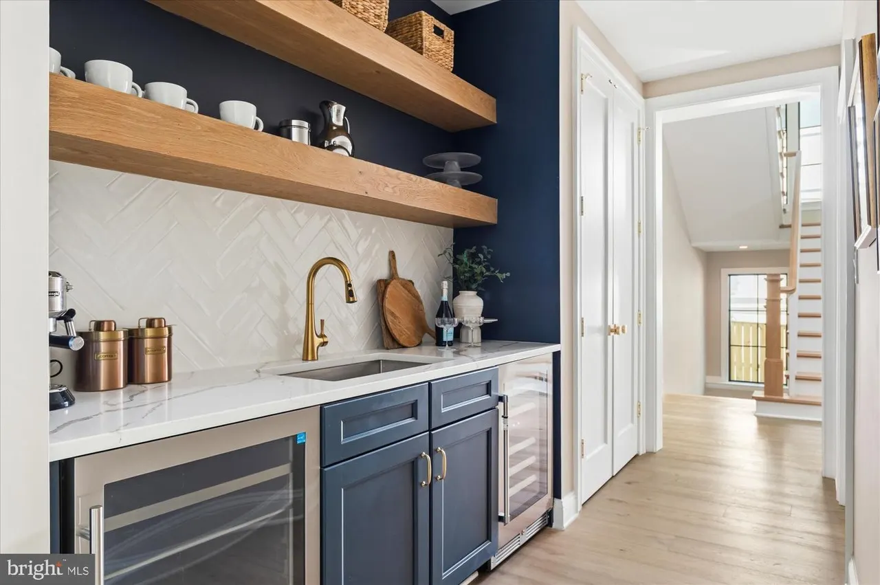 Butler's pantry with navy cabinetry, marble countertop, wooden shelves