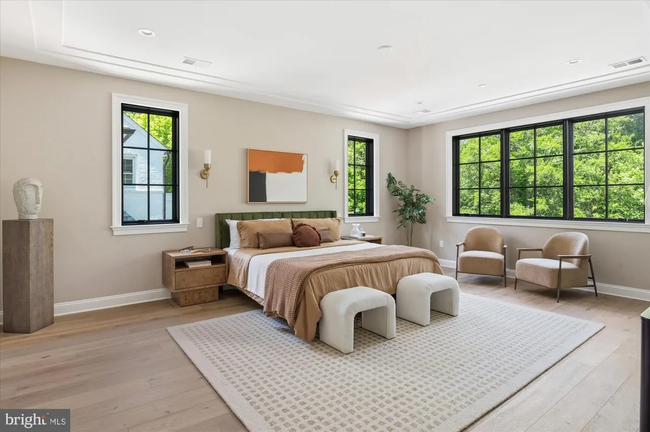 Primary bedroom with green headboard, wood nightstand, and large windows
