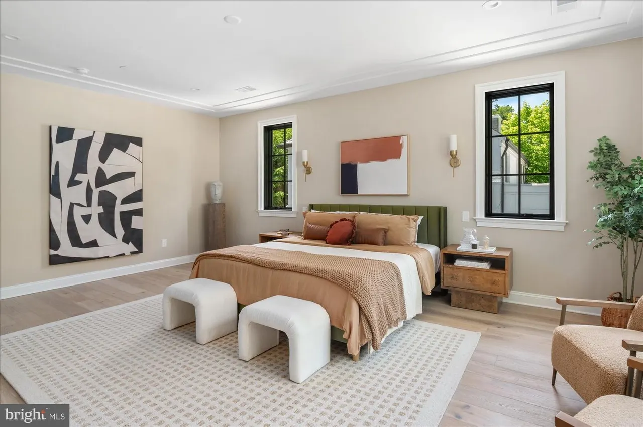 Bedroom with green headboard, cream bedding, and abstract artwork