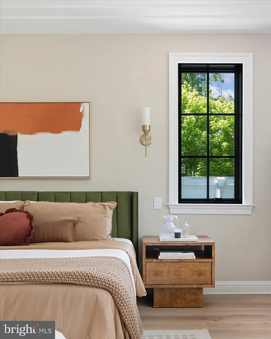 Bedroom corner with green headboard, black framed window, and nightstand