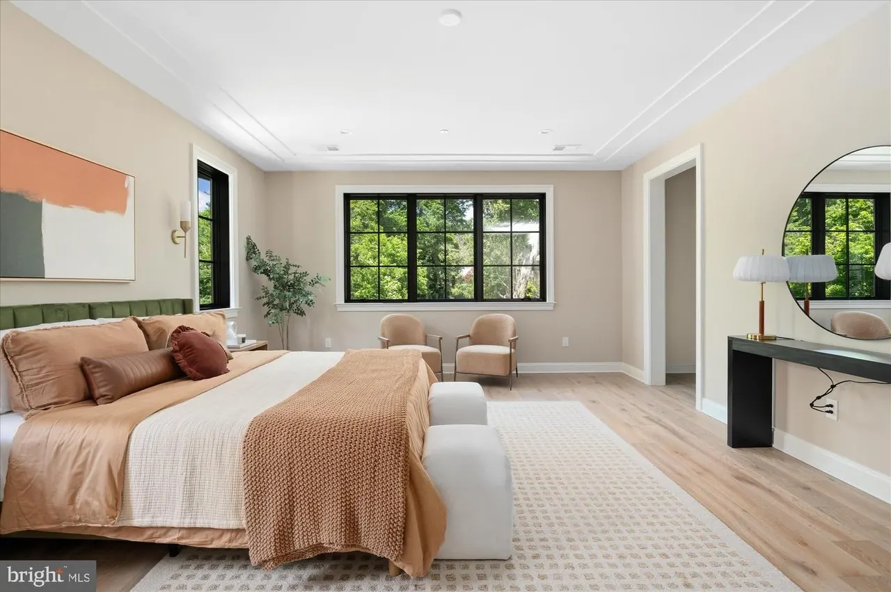 Spacious primary bedroom with vanity, seating area, and large windows