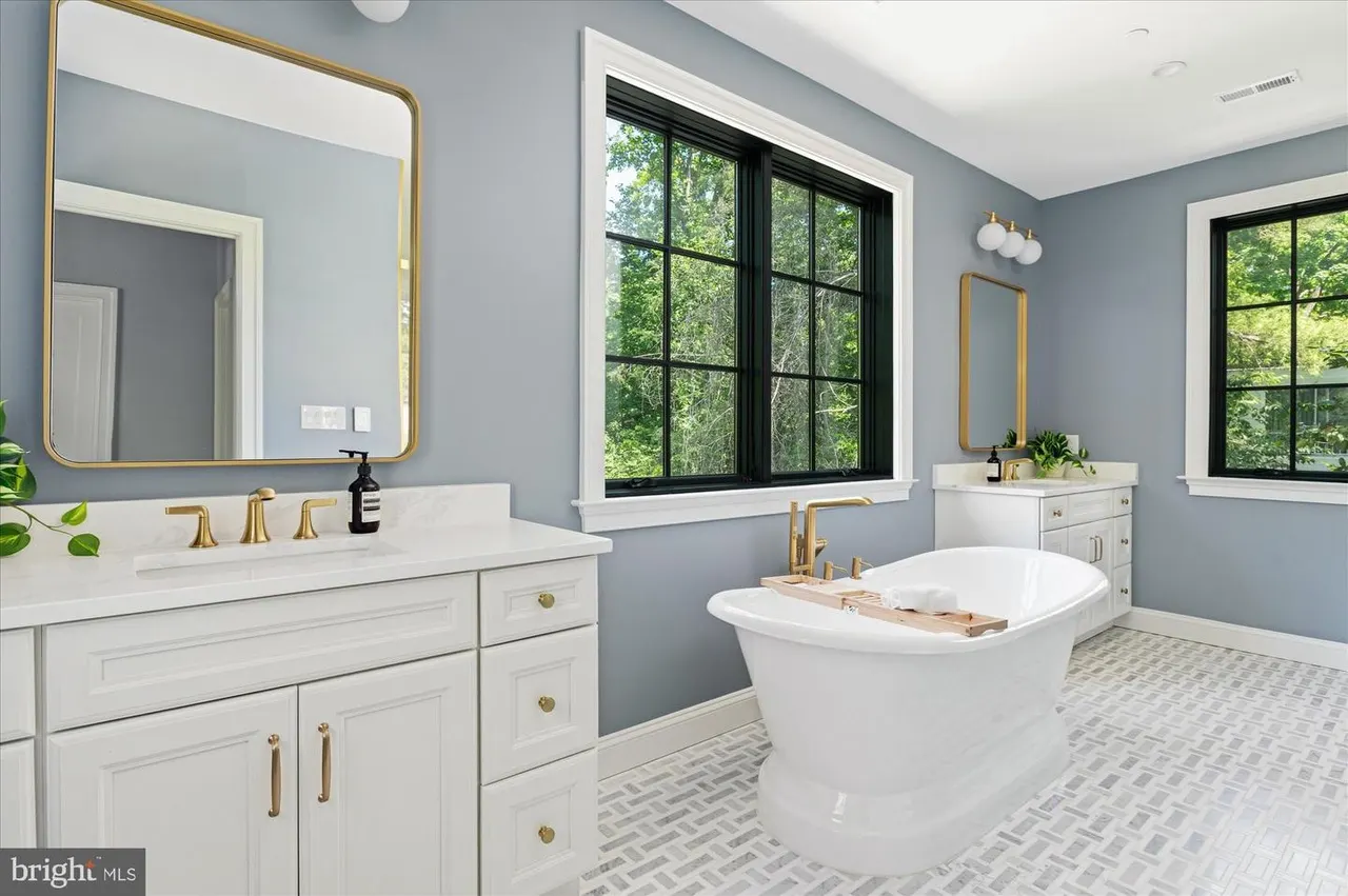 Master bath with white vanity, freestanding tub, and blue walls