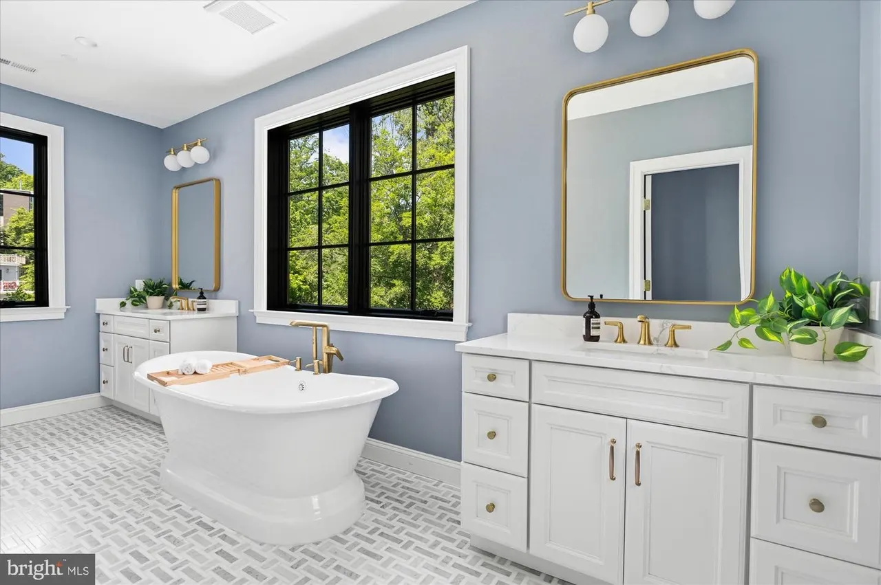 Bathroom with white vanities, freestanding tub, and blue walls