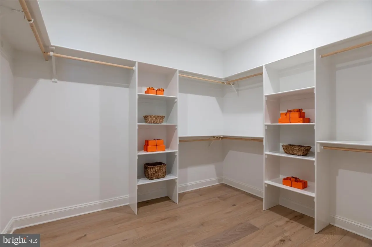 Walk-in closet with white shelving and wooden rods