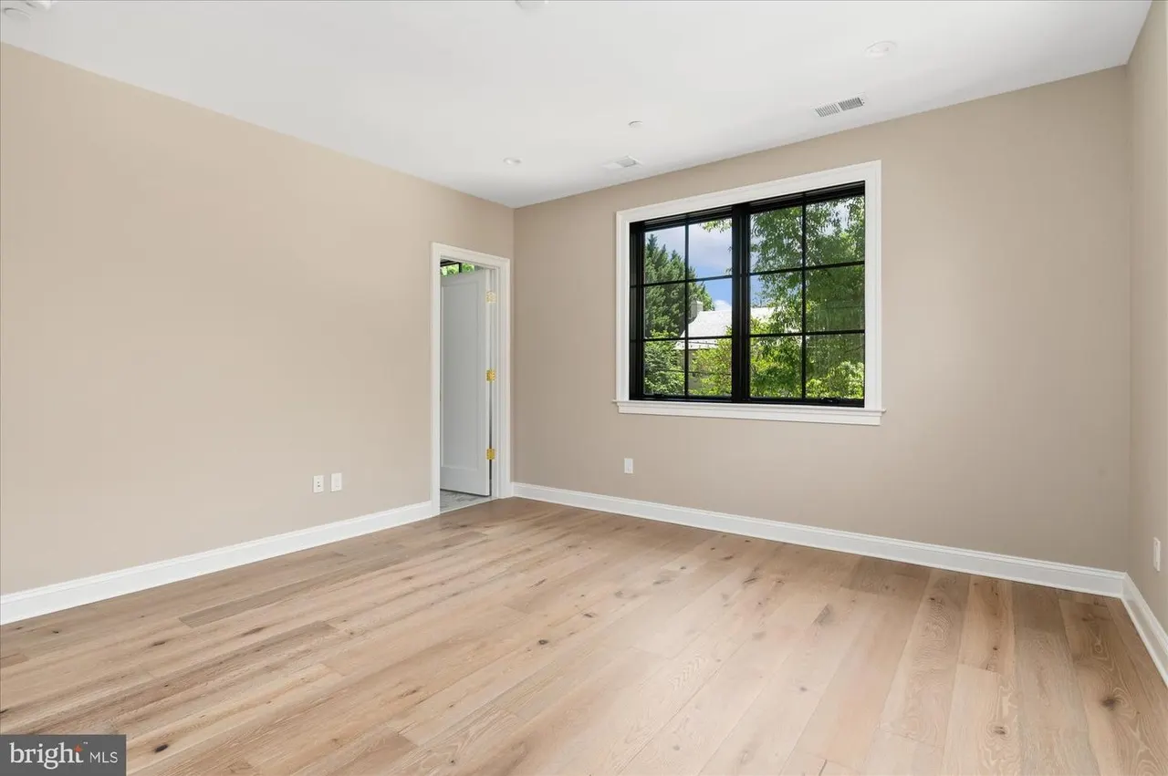 Empty bedroom with beige walls and hardwood floors