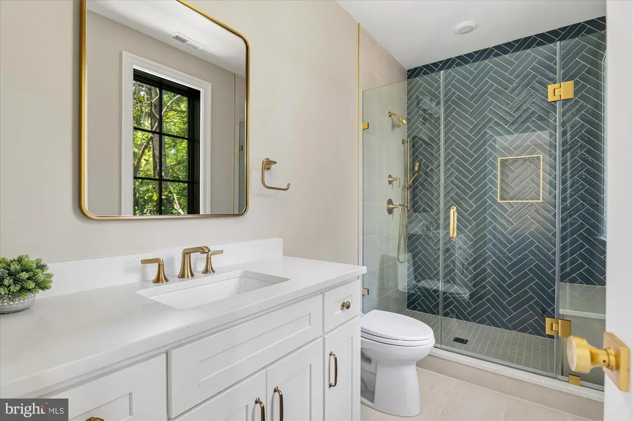 Bathroom with herringbone tile shower and white vanity