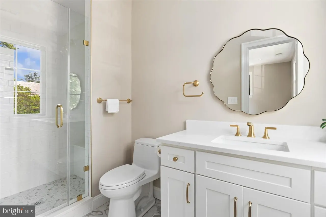 Bathroom with white vanity, scalloped mirror, and glass shower enclosure