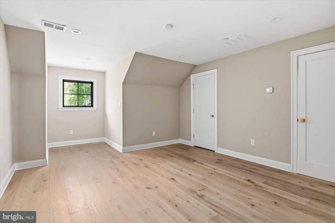 Bedroom with vaulted ceiling, hardwood floors, and natural light