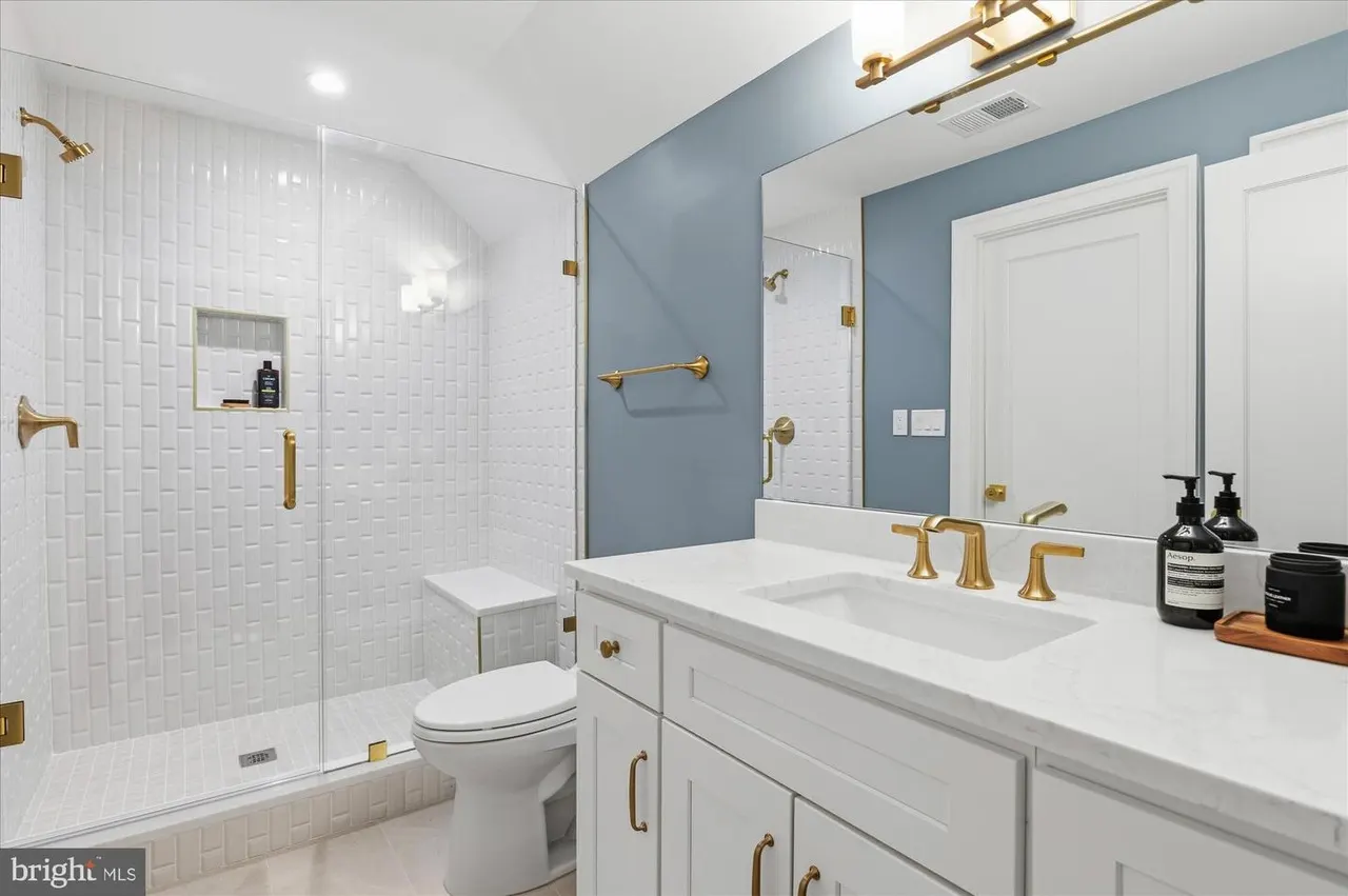 Bathroom with white tile shower, blue walls, and brass fixtures