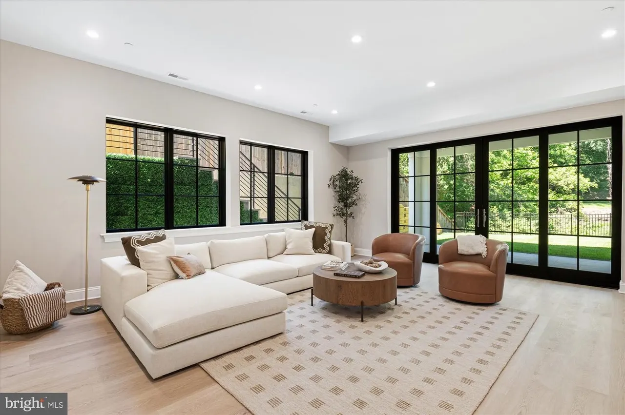 Great room with cream sectional, leather chairs, and glass doors to outdoor space