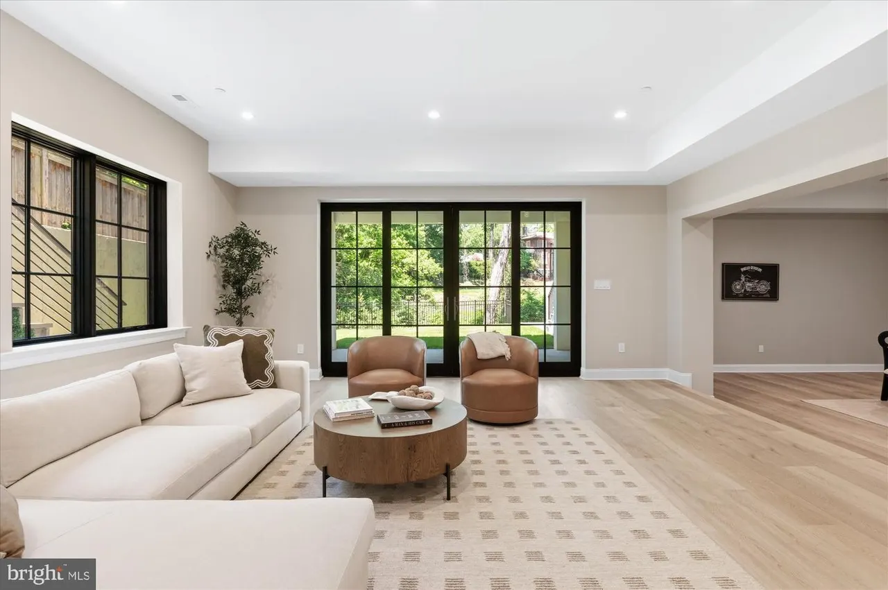 Family room with cream sofa, brown chairs, and multi-pane glass doors