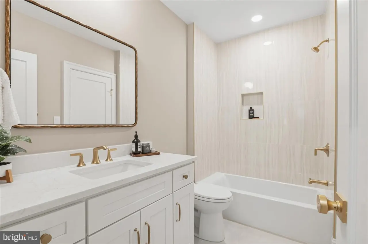 Primary bathroom with white vanity, brass fixtures, and tile shower