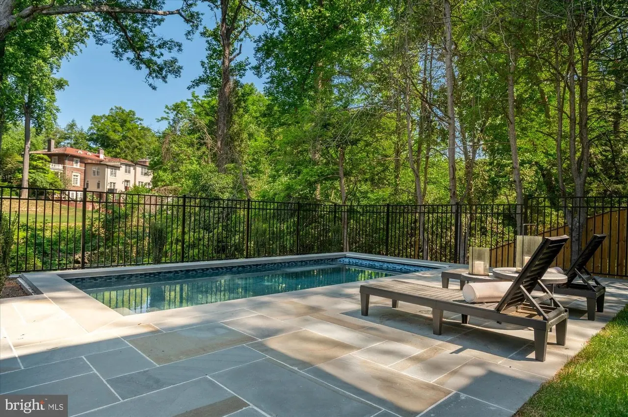 Swimming pool with lounge chairs and wooded backdrop