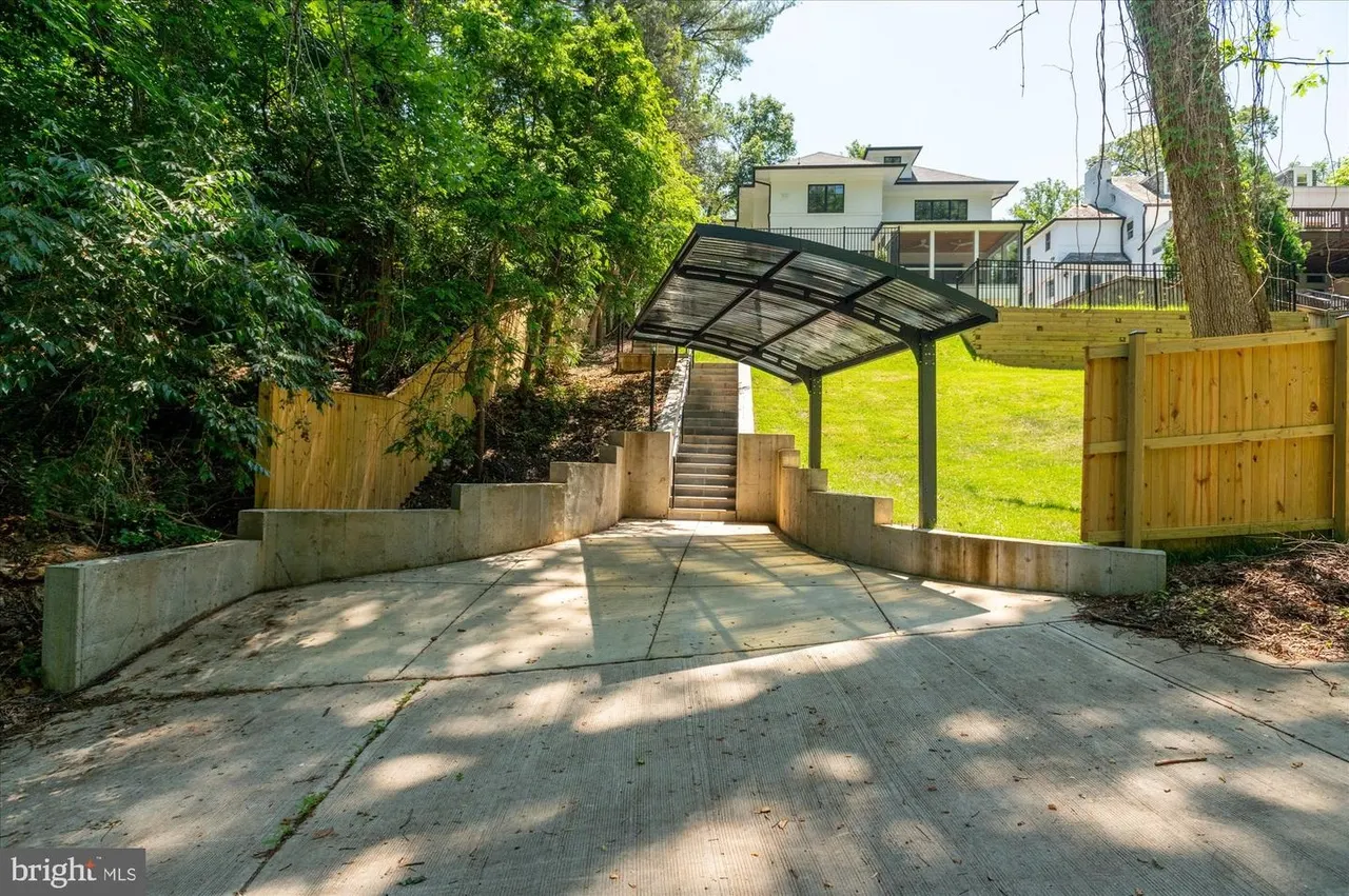 Driveway with pergola, wooden fence, and concrete retaining walls