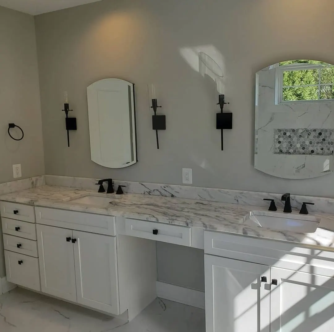 Double vanity with marble counters, arched mirrors, and black fixtures