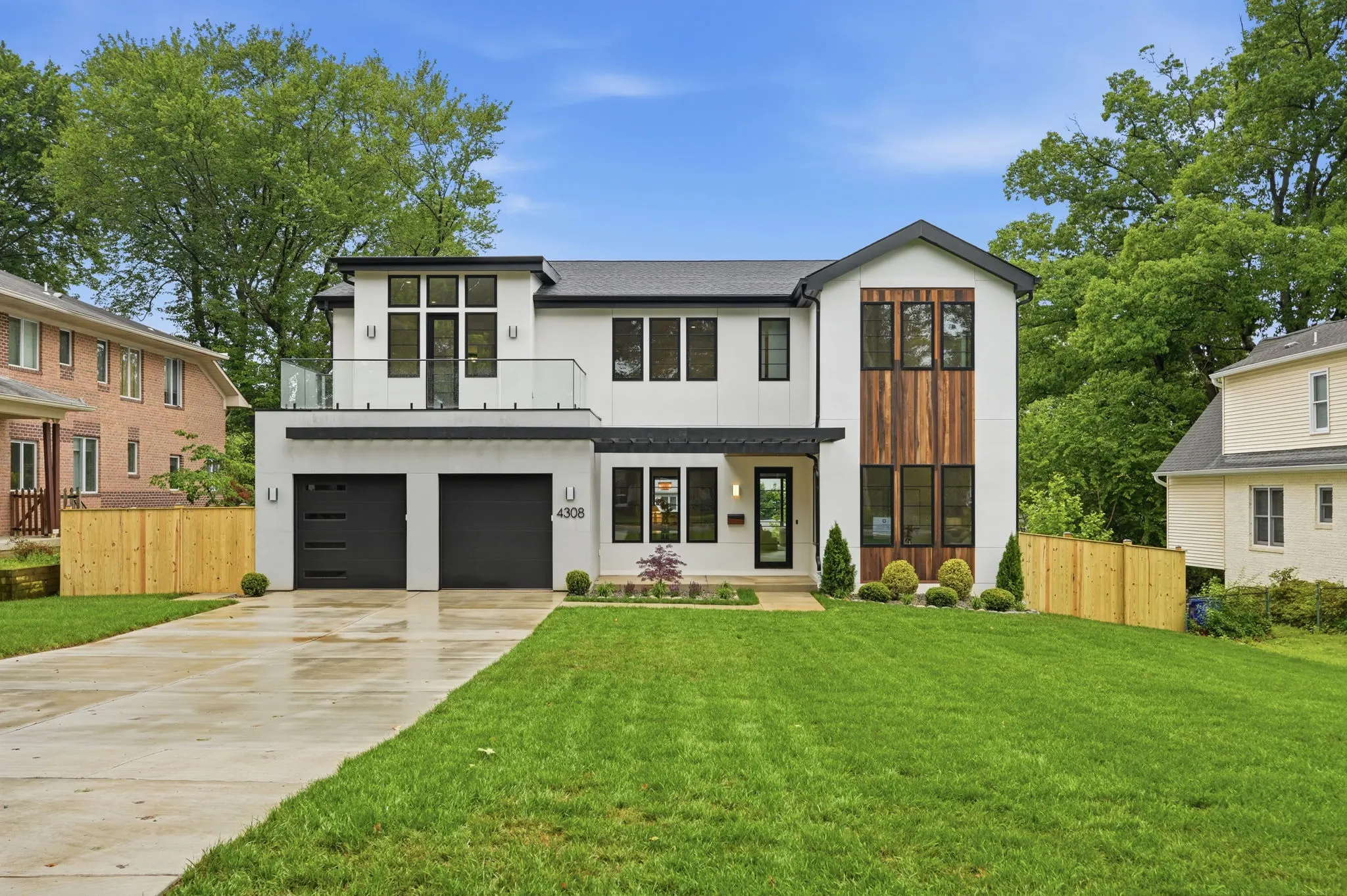 Modern white house with dark garage doors and landscaped yard