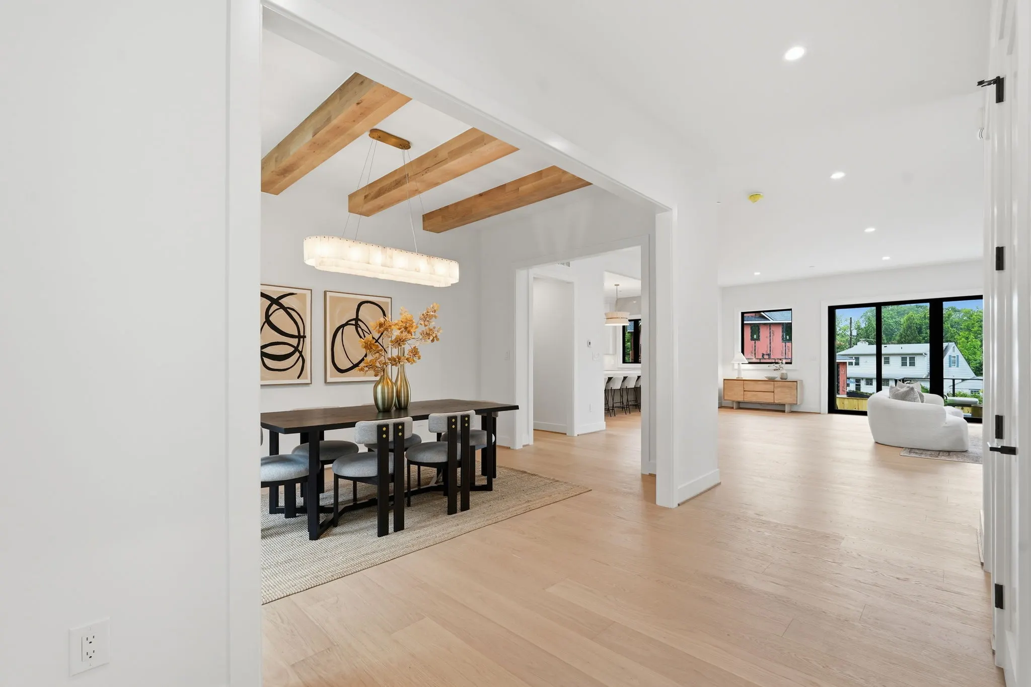 Open concept living and dining space with exposed wood beams