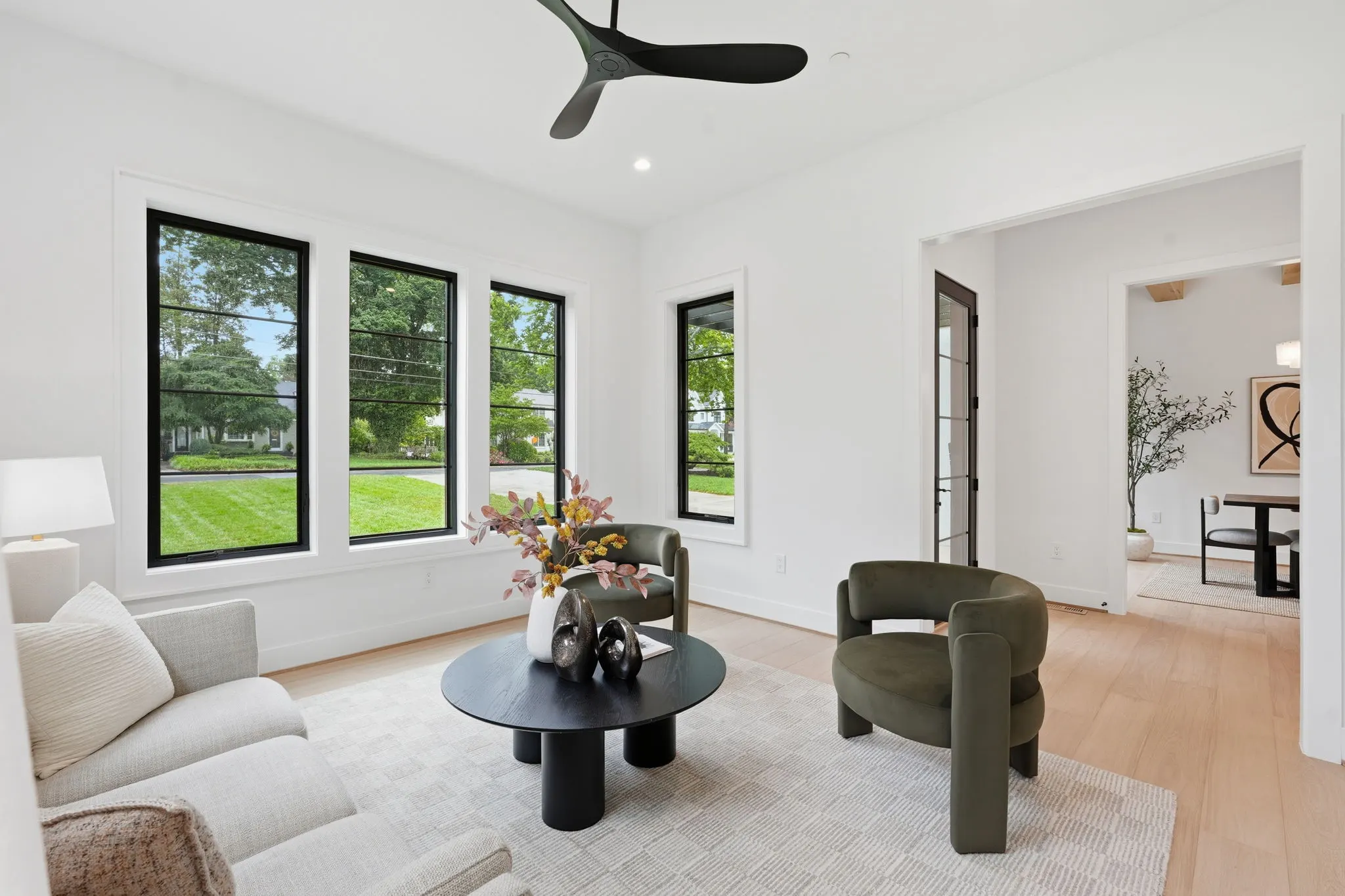 Living room with black ceiling fan, large windows and contemporary furniture