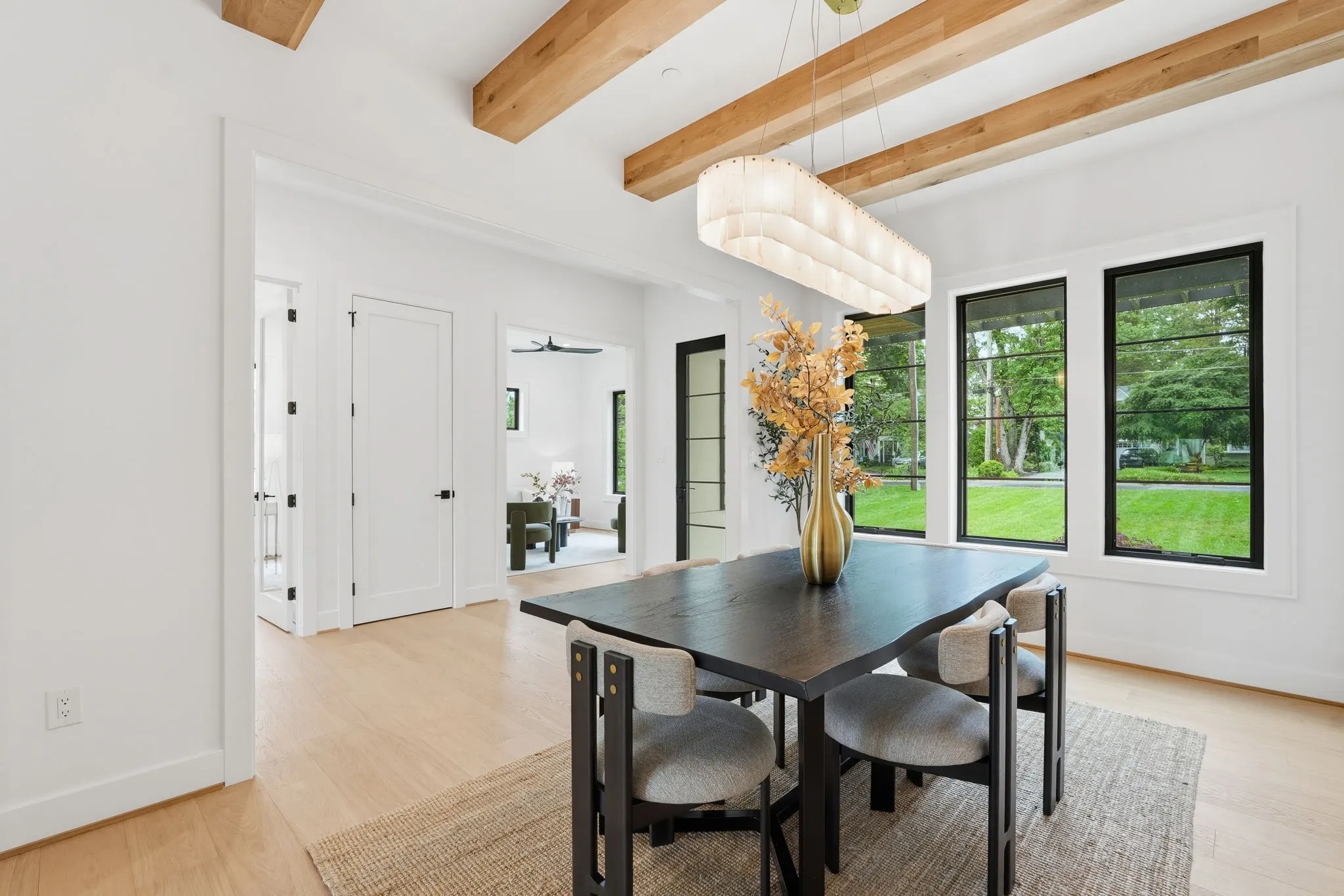 Dining area with exposed beams and large windows overlooking yard