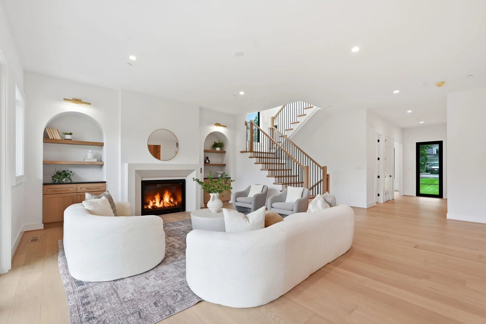 Living room with fireplace, white seating, and open staircase