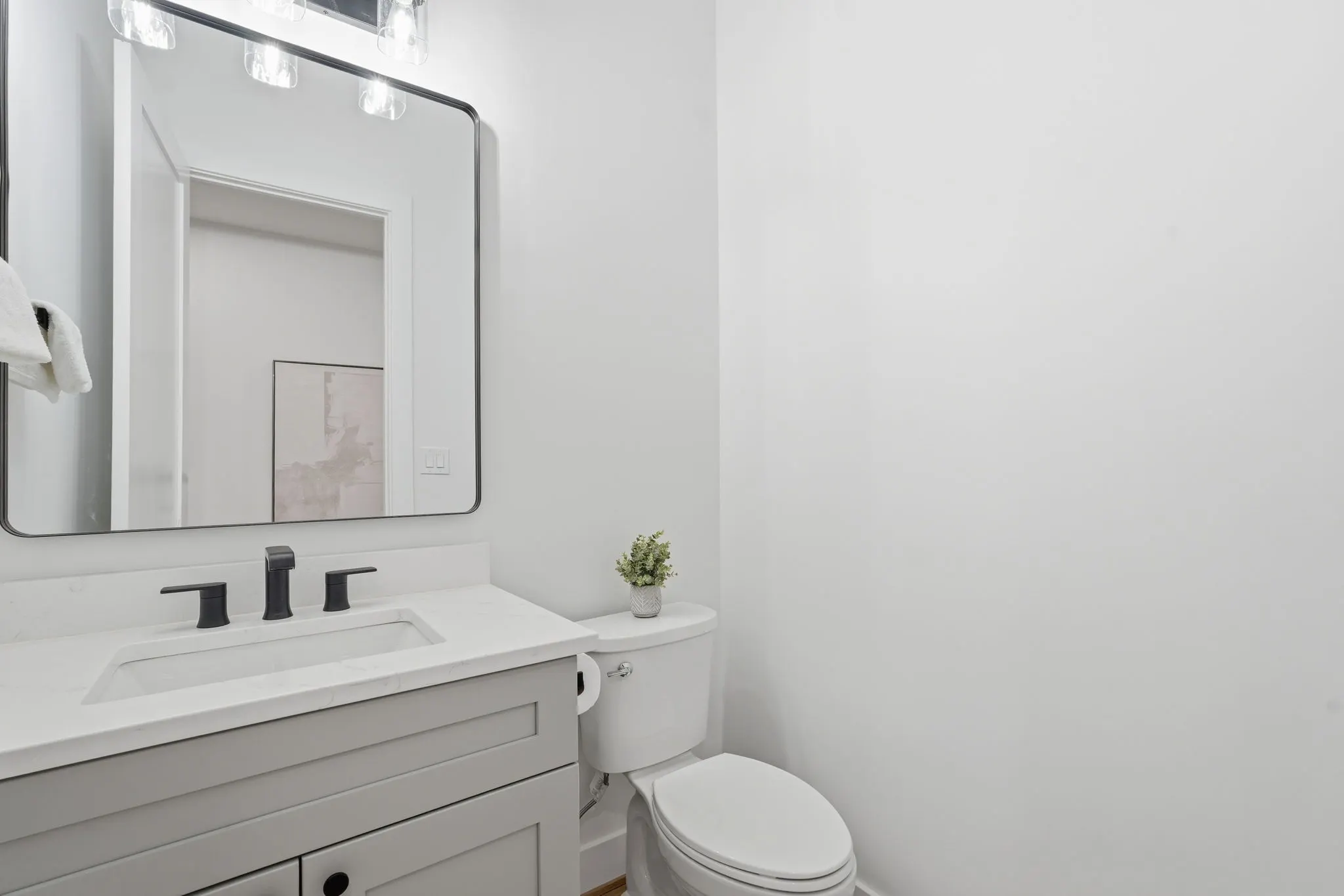 Bathroom with white vanity, black fixtures, and rectangular mirror